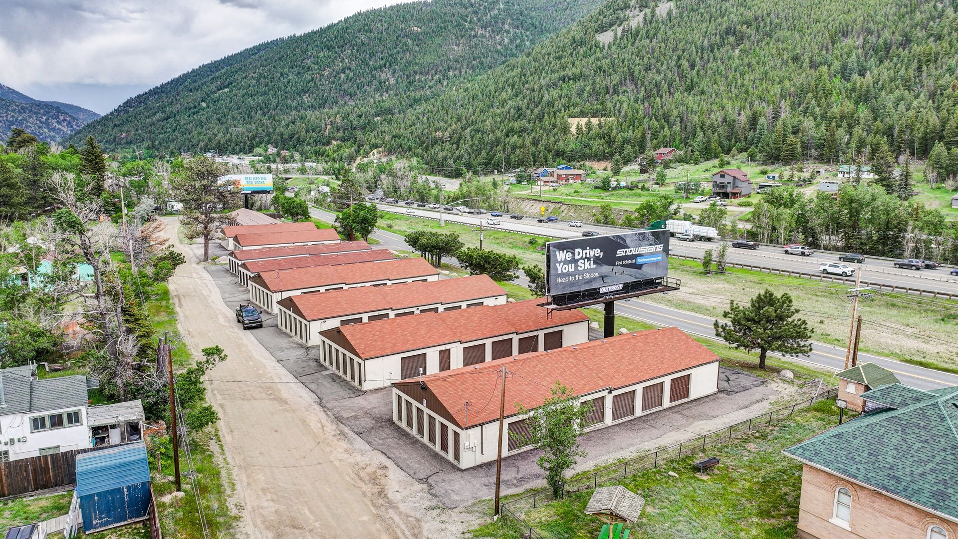 Storage units nestled among trees in a green, mountainous setting.