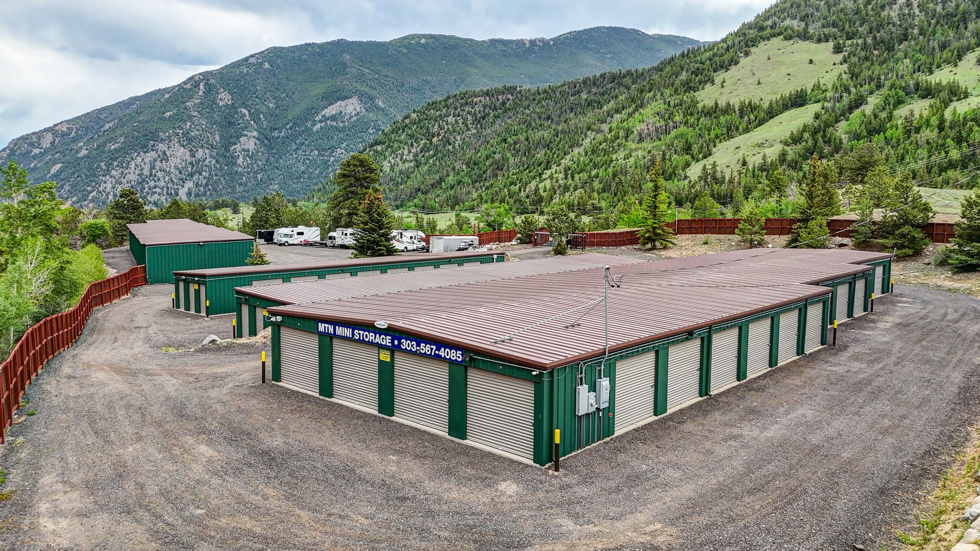 Storage units nestled among trees in a green, mountainous setting.