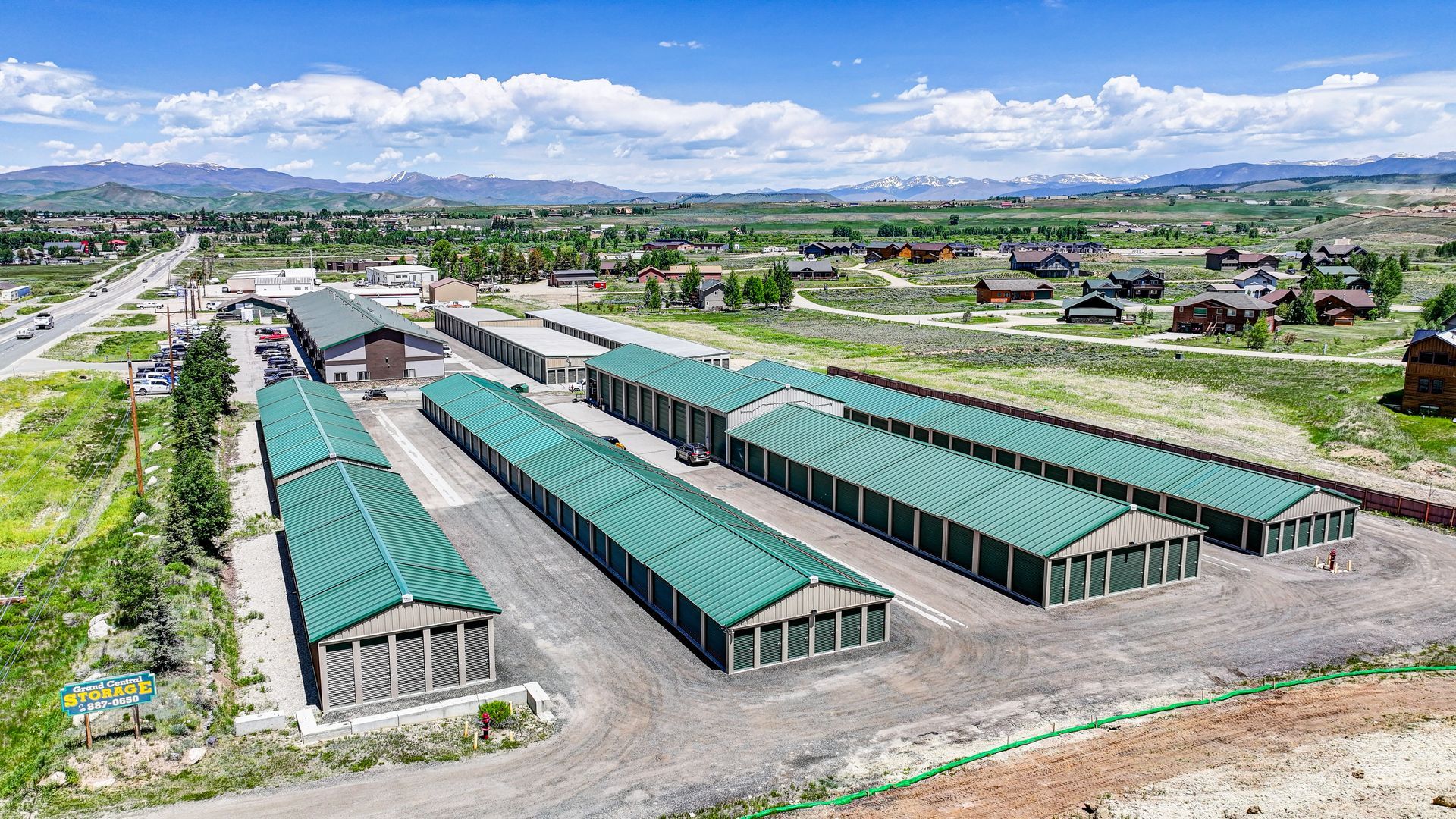 Storage units nestled among trees in a green, mountainous setting.
