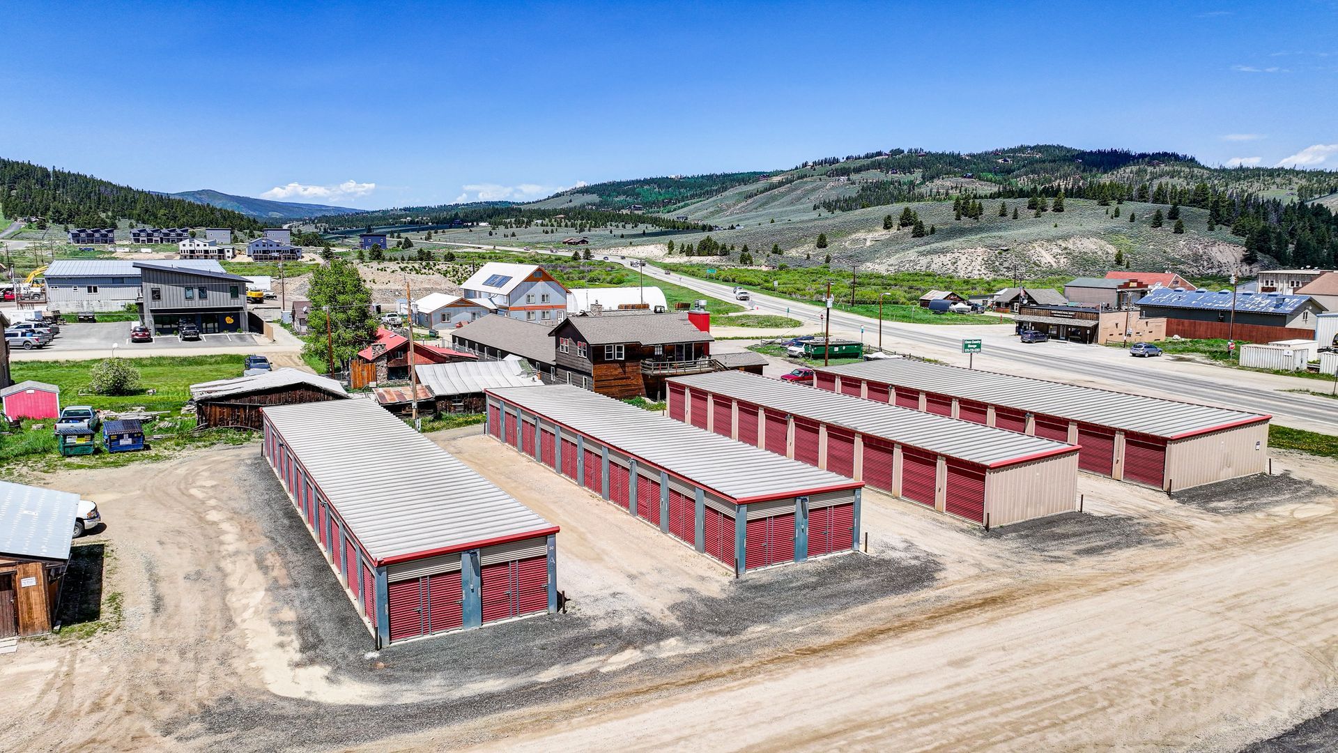 Photo of storage red storage facility with mountains in background. 