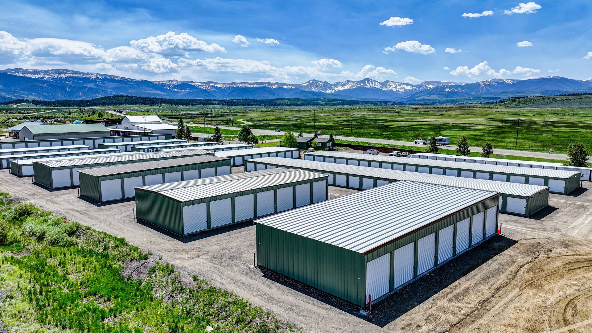 Storage units nestled among trees in a green, mountainous setting.