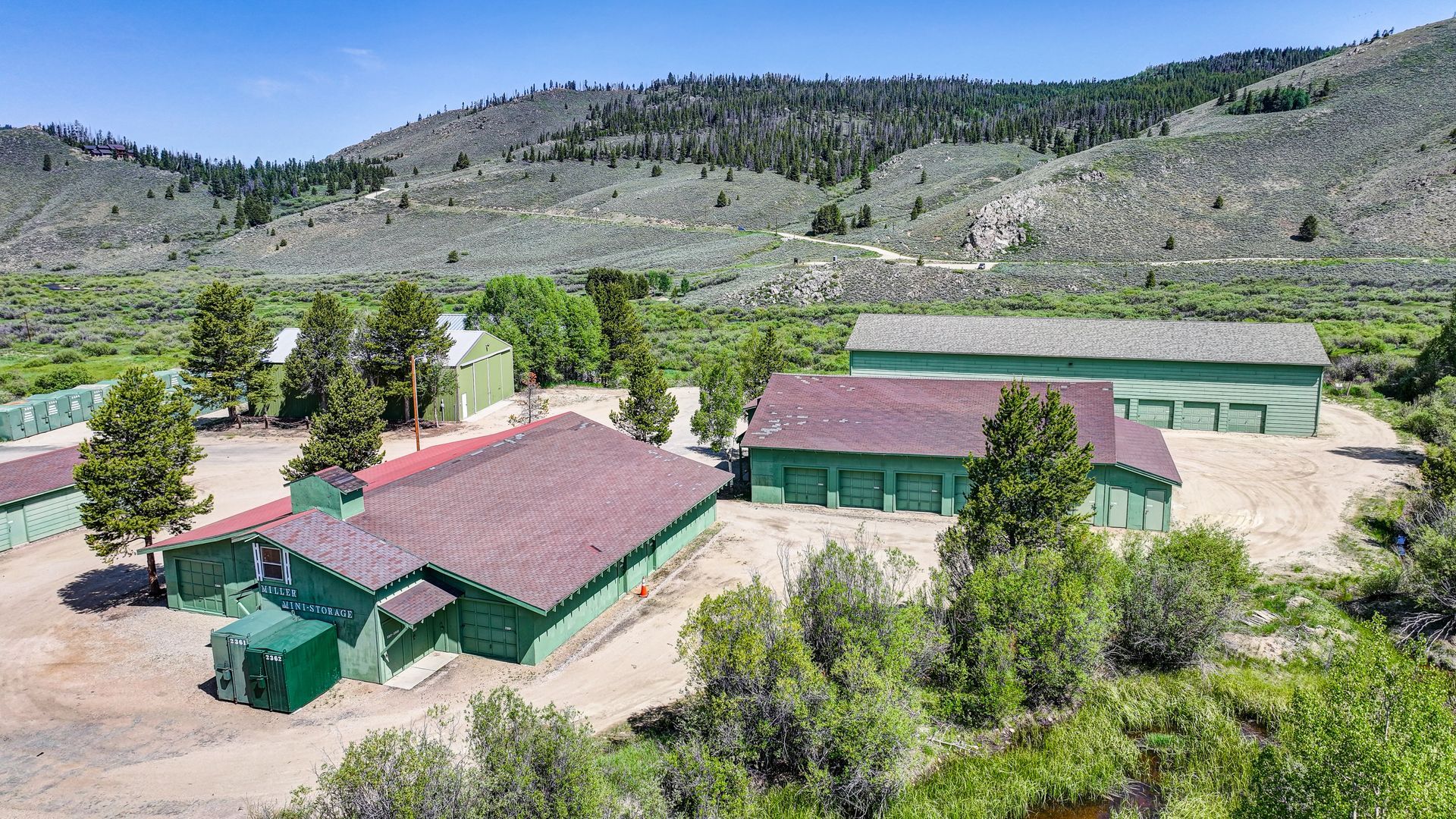 Storage units nestled among trees in a green, mountainous setting.