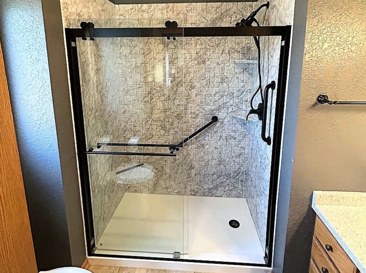 A bathroom with a walk in shower with a sliding glass door