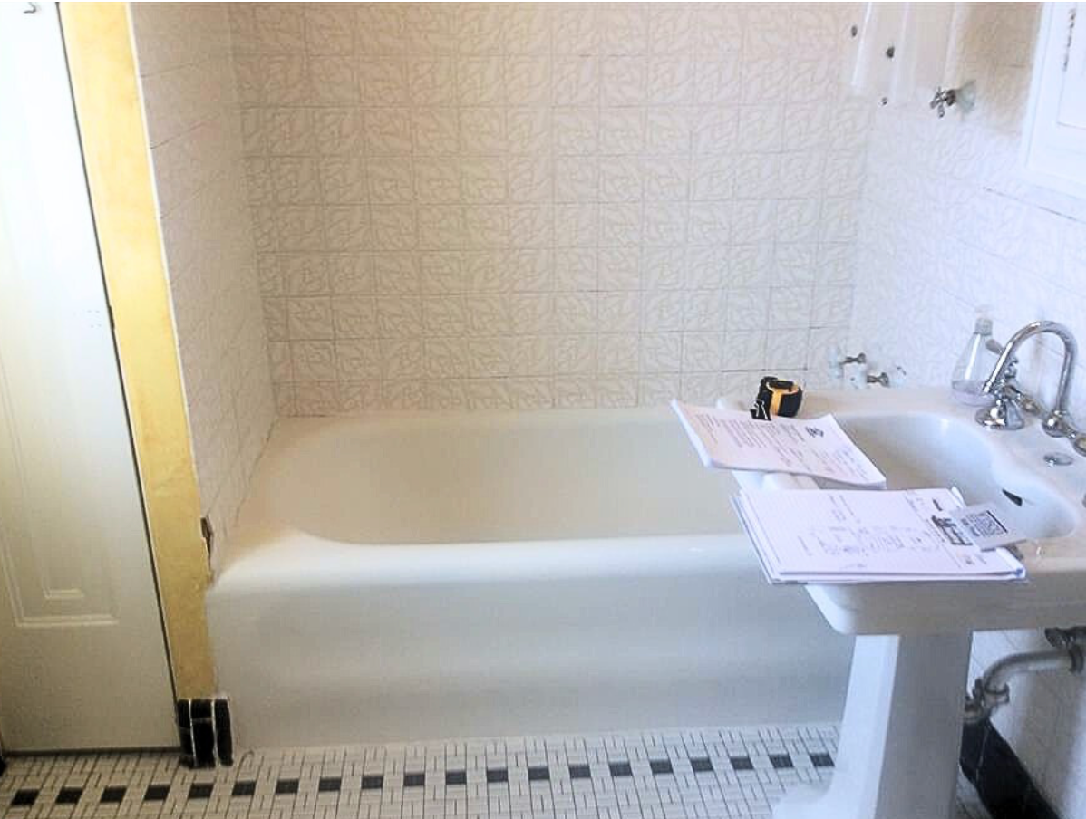 A bathroom with a bathtub, sink, and mirror