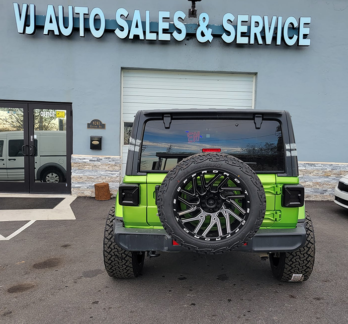 Green Jeep Wrangler with black accents parked in front of VJ Auto Sales & Service building. | VJ Auto Sales & Service
