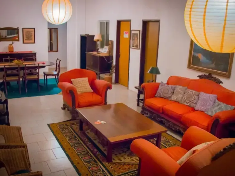 Sala de estar com móveis laranja, área de jantar, tapete e lanternas de papel.