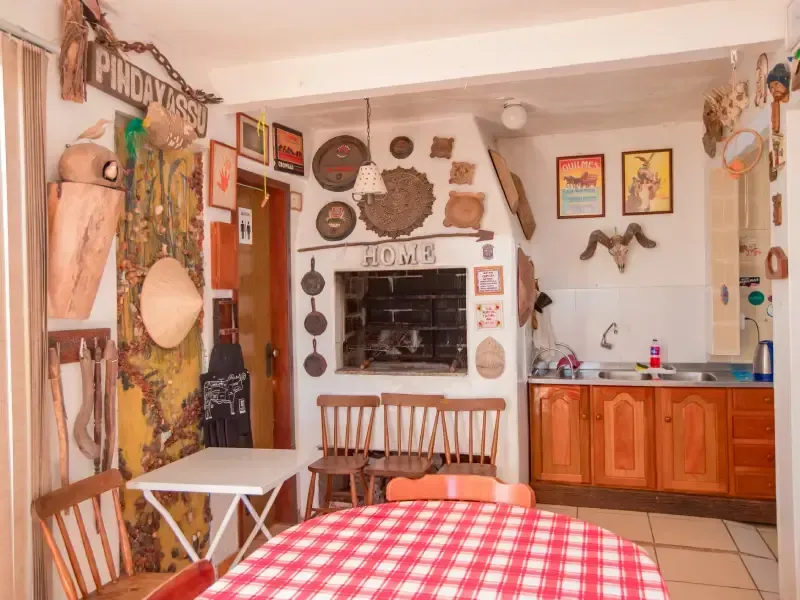 Cozinha rústica com churrasqueira, móveis de madeira e paredes decoradas com objetos vintage.