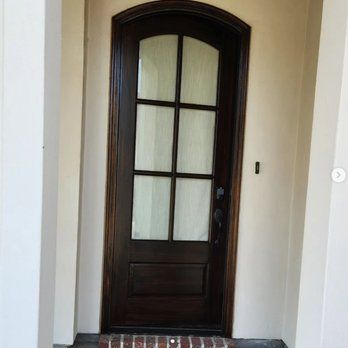 A wooden door with a glass window and a brick floor.