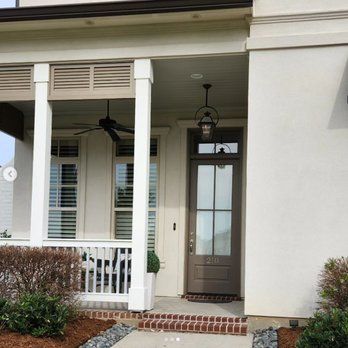 A white house with a porch and a ceiling fan.