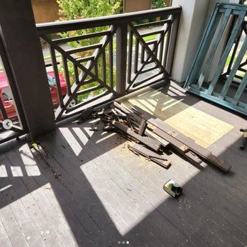 A balcony with a metal railing and wooden boards on the floor.