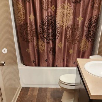 A bathroom with a toilet , sink , bathtub and shower curtain.