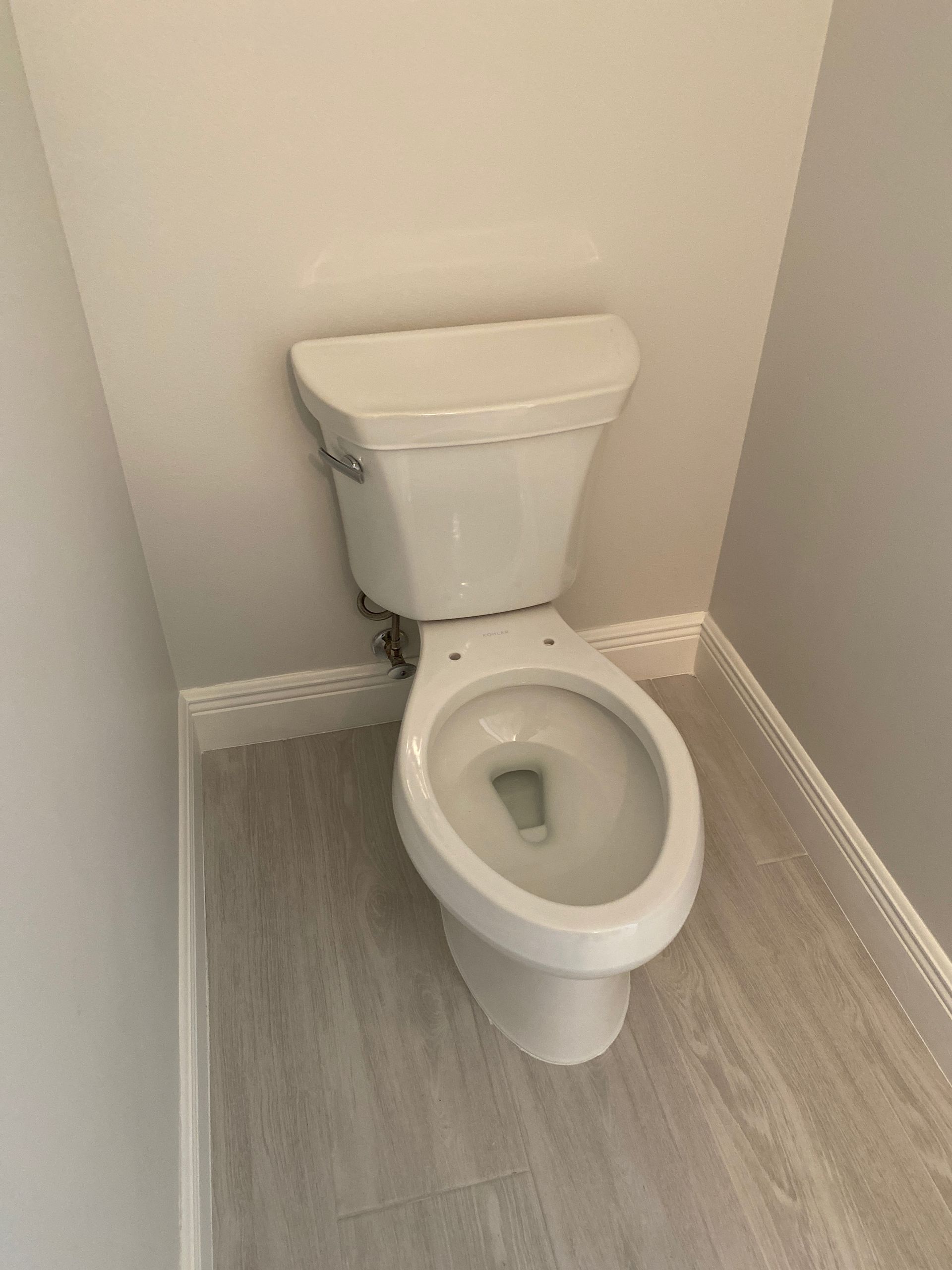 White toilet in a small bathroom with light gray walls and floor.