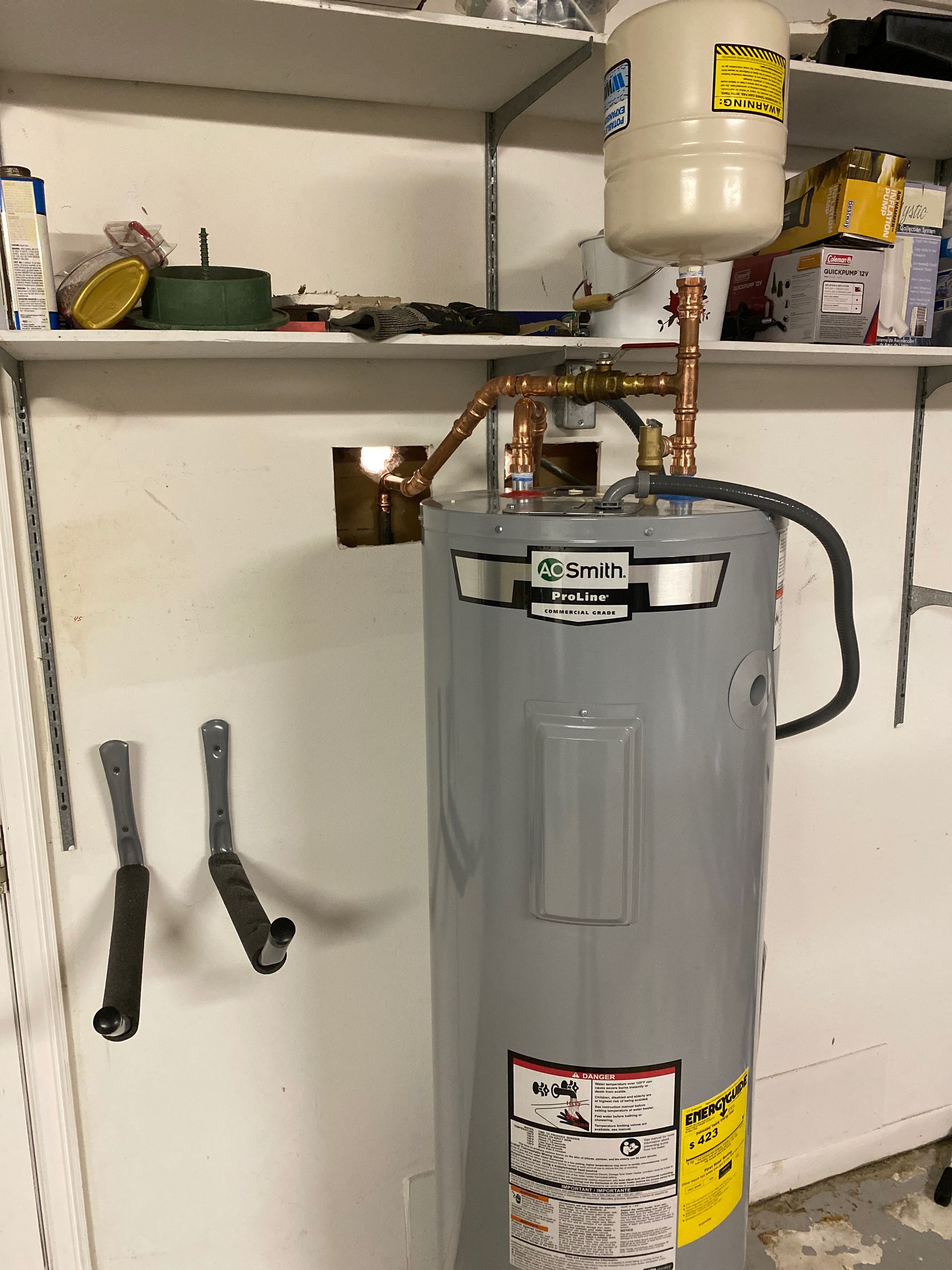 Water heater with expansion tank, copper pipes, mounted on a wall.