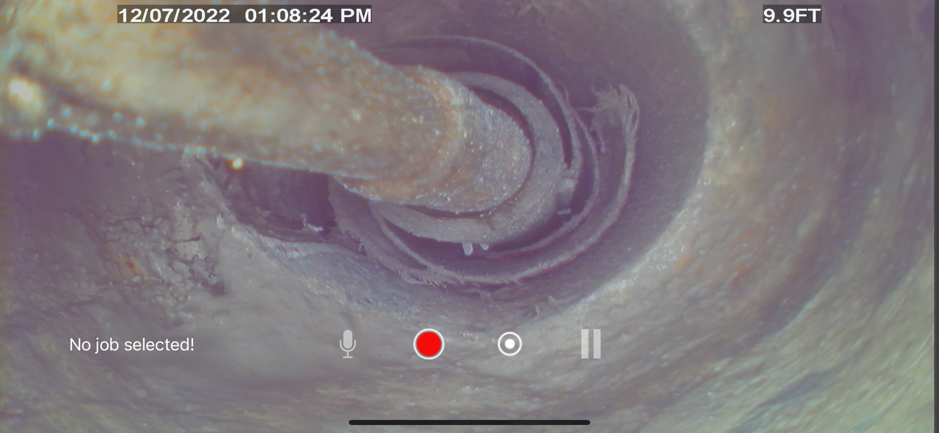 A camera view of a pipe interior, showing a rusty metal rod and a spiraling interior.