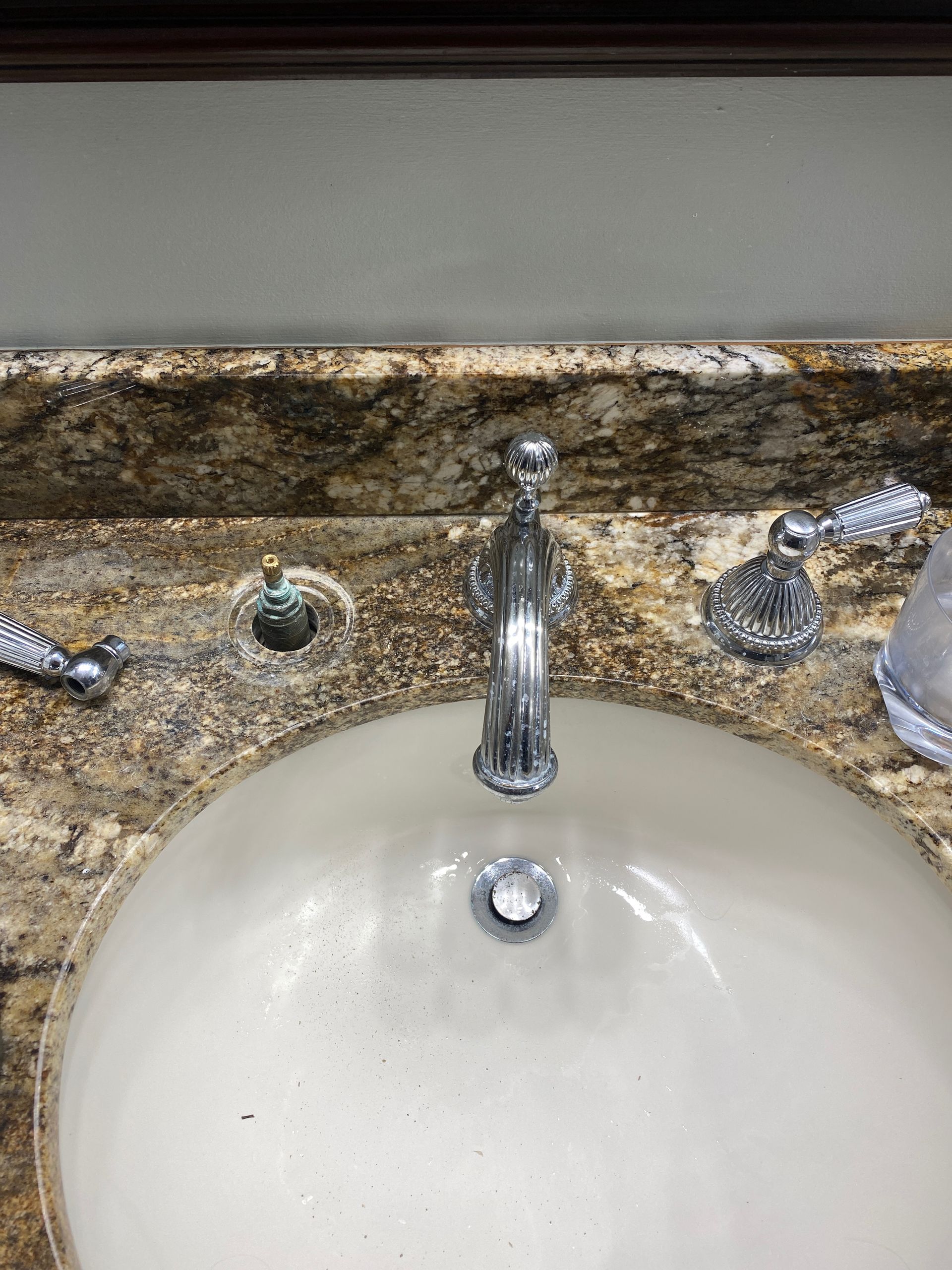 Bathroom sink with ornate faucet, a granite countertop, and a white basin.