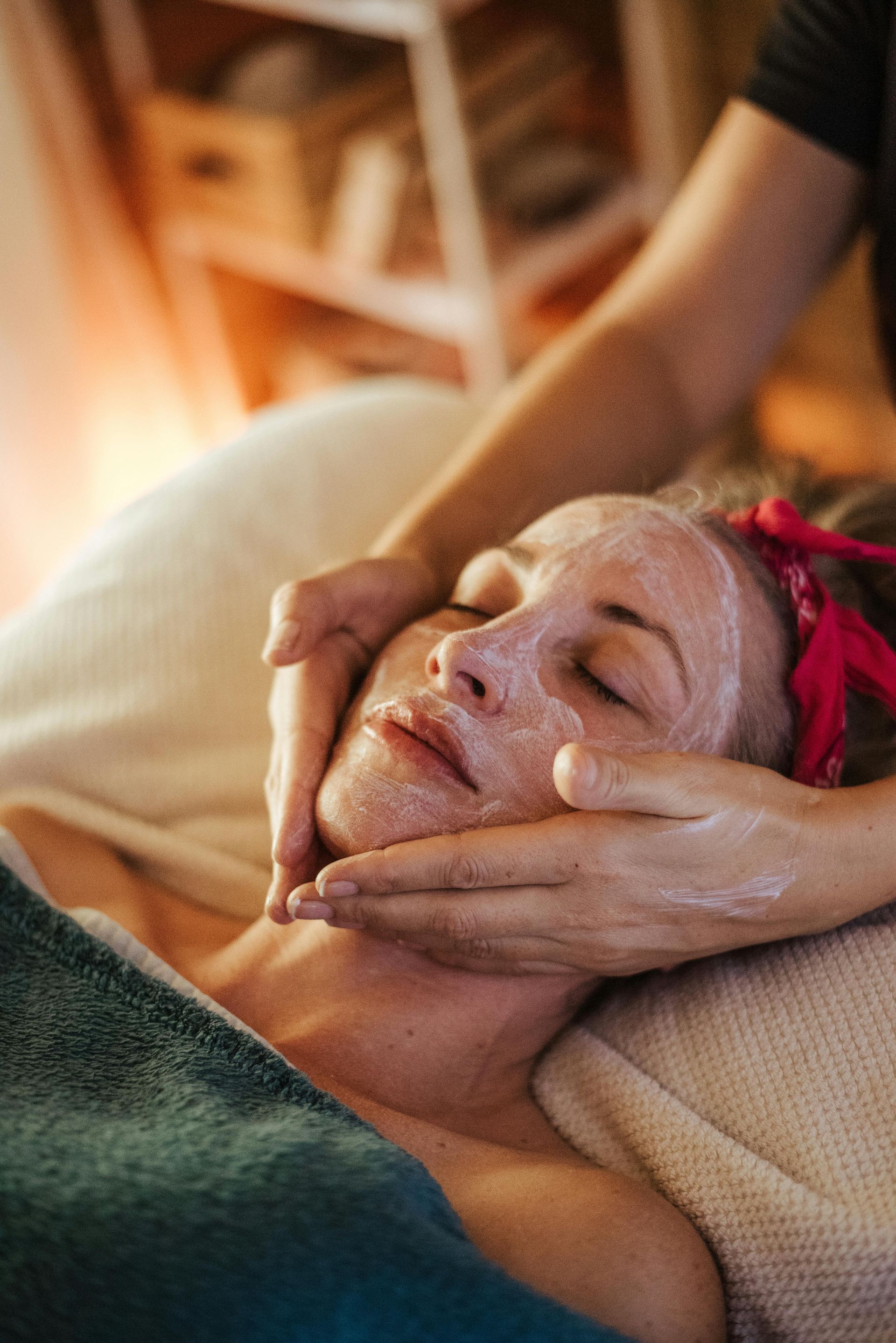 Woman receiving a facial treatment with hands massaging her face.