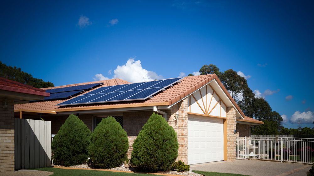 A House With Solar Panels on the Roof and a White Garage Door — Spot On Solar International in Beresfield, NSW