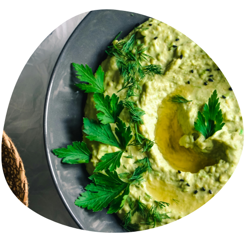 A wooden cutting board topped with zucchini chips and a bowl of dip