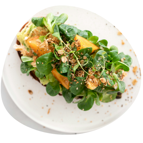 A wooden cutting board topped with zucchini chips and a bowl of dip