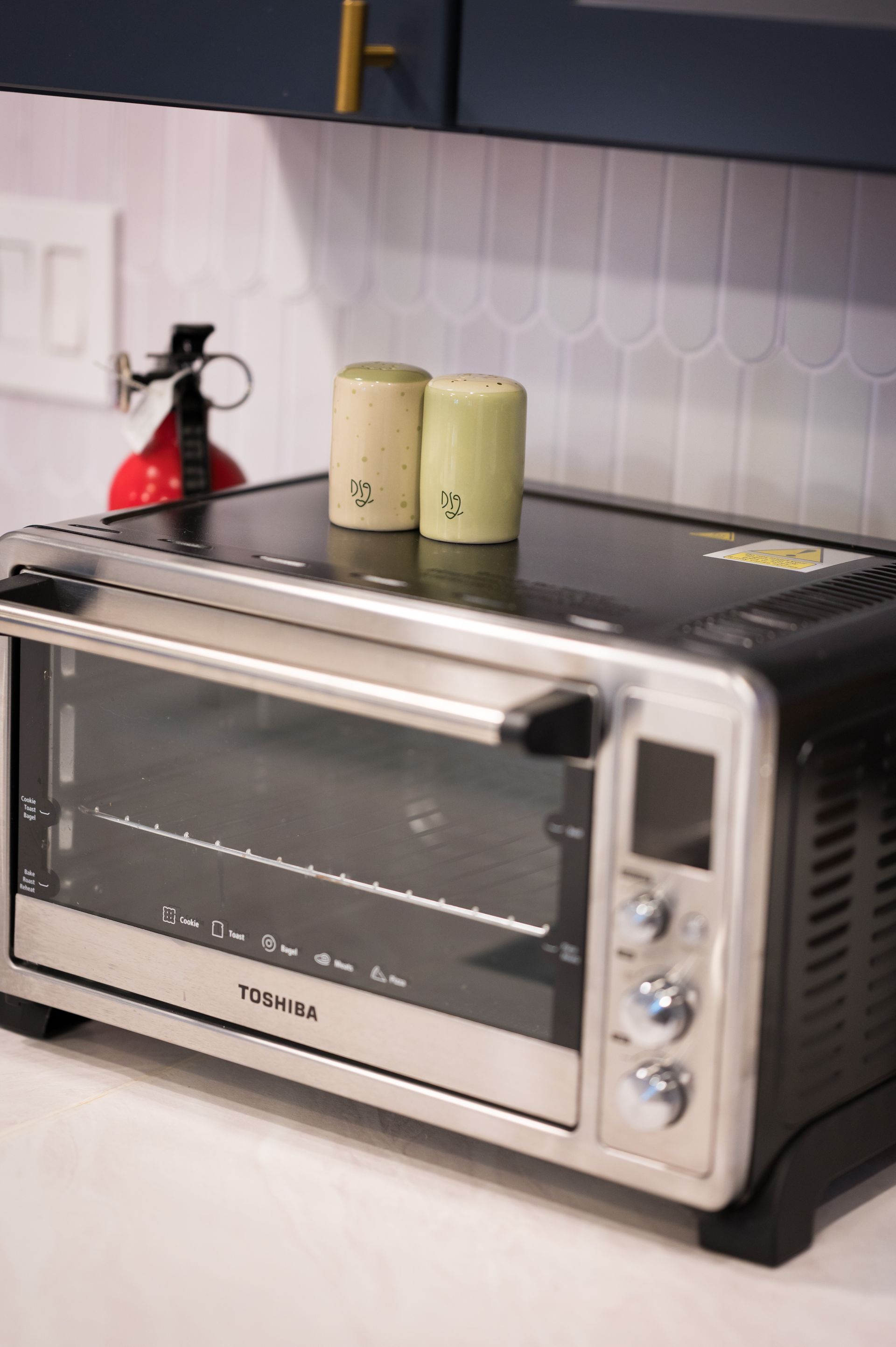 A toaster oven with salt and pepper shakers on top, kitchen setting.