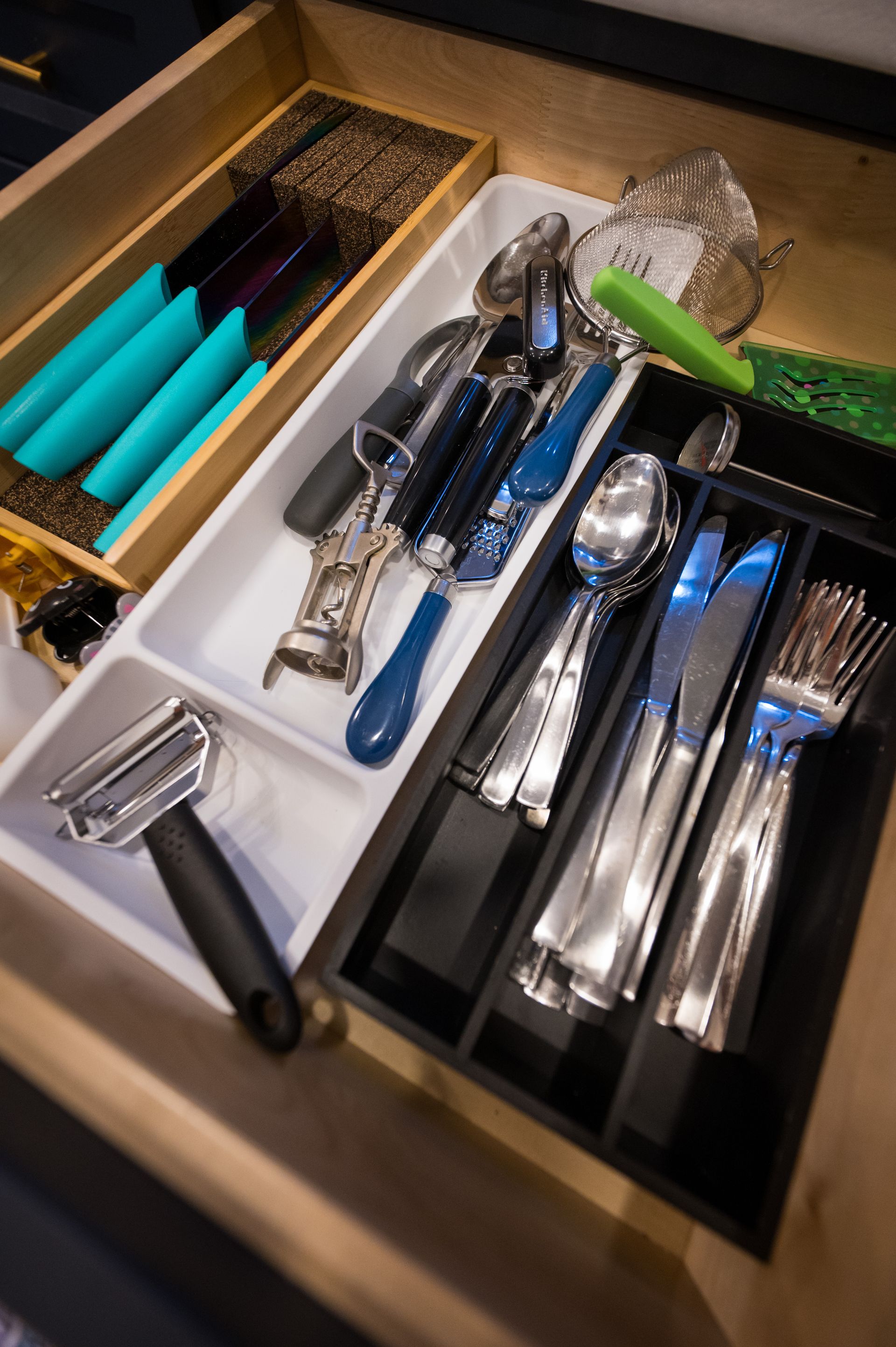 Open kitchen drawer with silverware, utensils, and organizer trays.