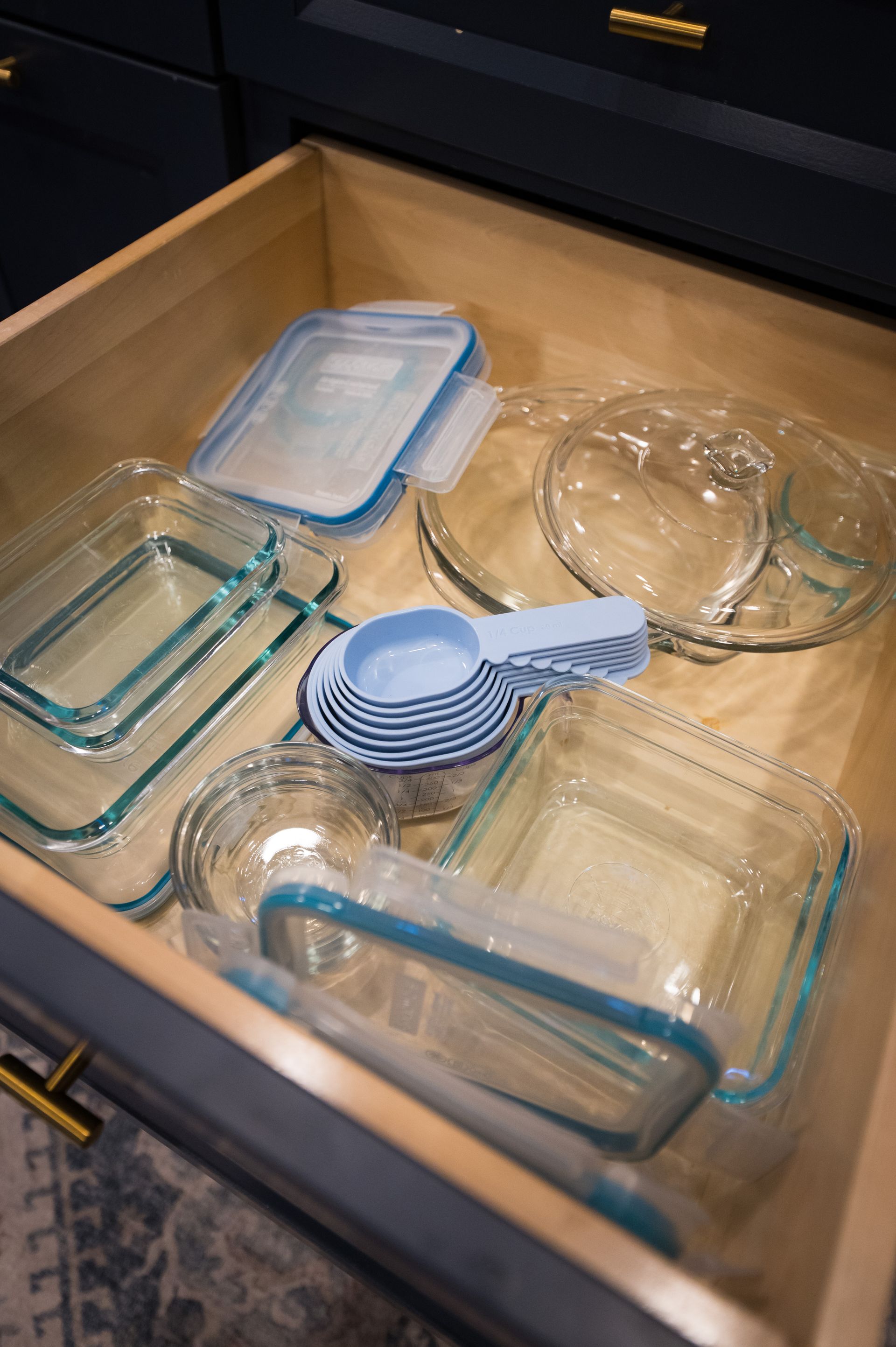 Drawer filled with glass food storage containers and blue measuring cups.