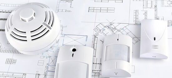 A Smoke Detector and a Motion Sensor are Sitting on top of a Blueprint — Electronic Security in Tweed, NSW