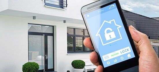A Person is Holding a smart Phone in Front of a House — Electronic Security in Tweed, NSW