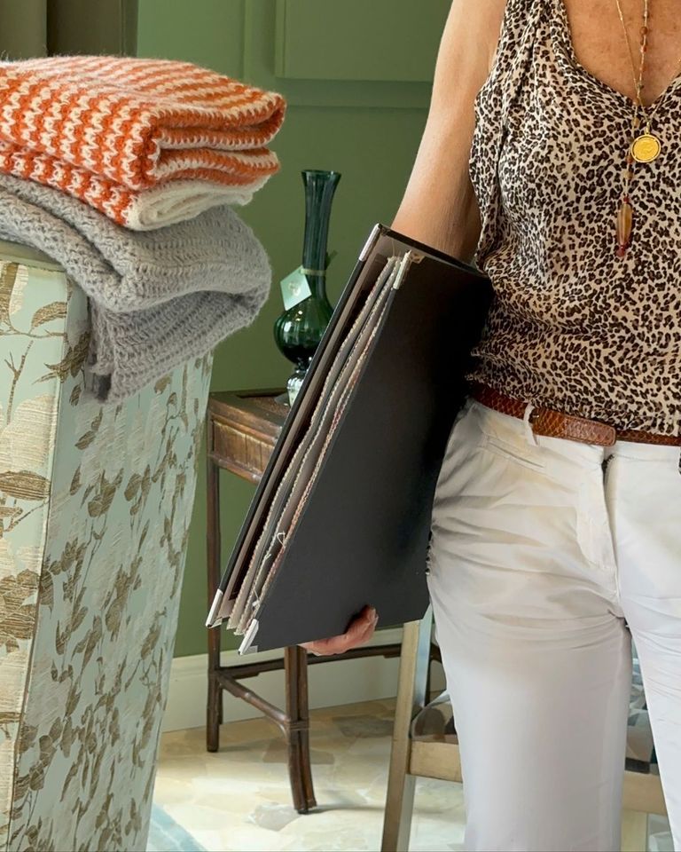 Una donna con un top leopardato tiene in mano una pila di riviste