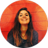 Woman with brown hair smiles in front of a red wooden wall.