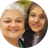 Woman with white hair smiling next to a younger person with long brown hair, both outdoors.