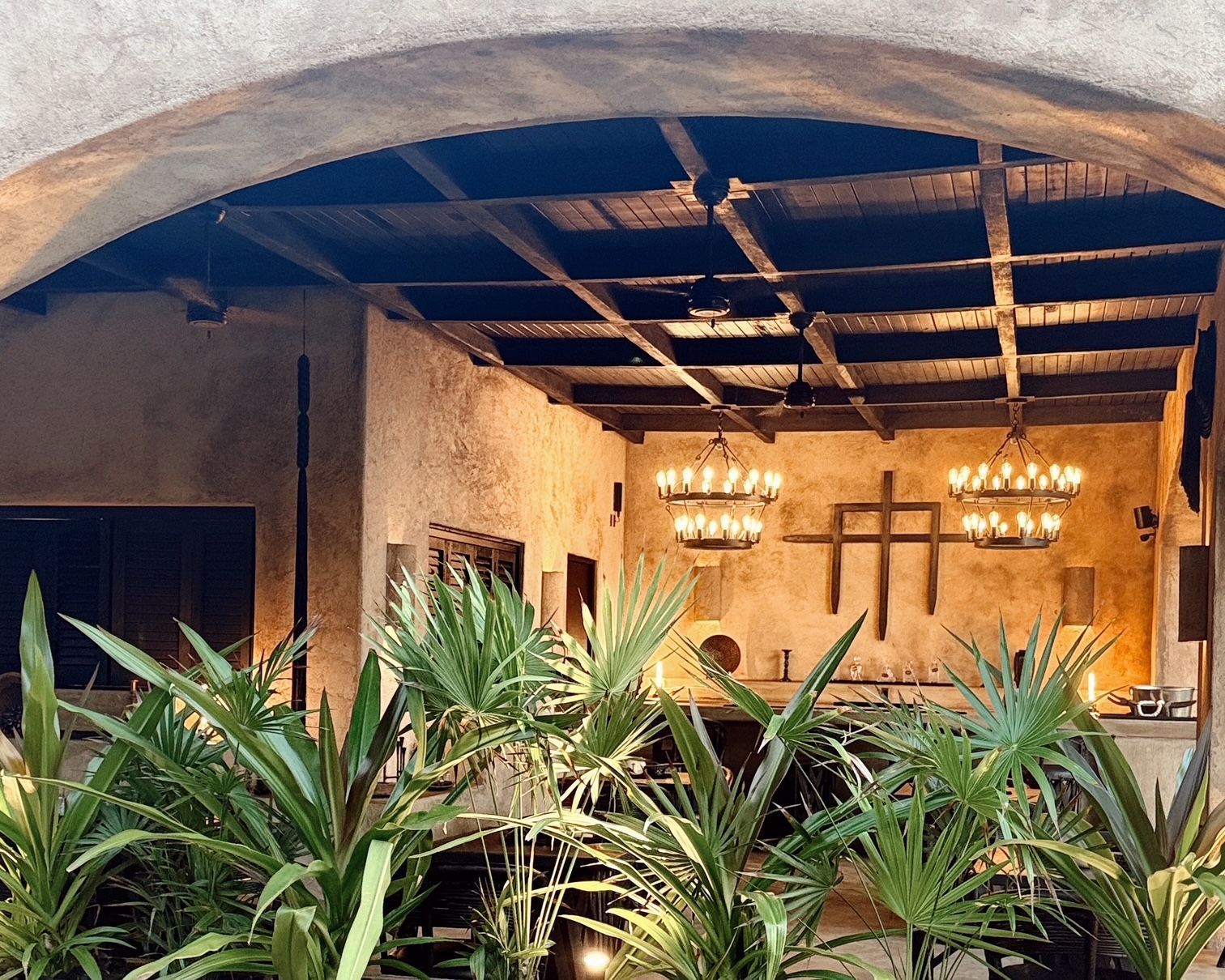 A room with a wooden ceiling and palm trees in front of it