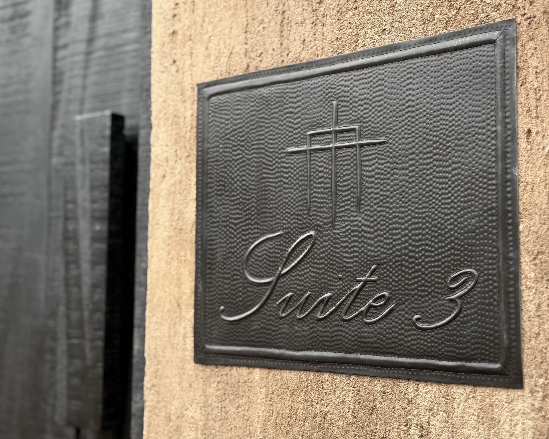 A black sign on a wall that says suite 3