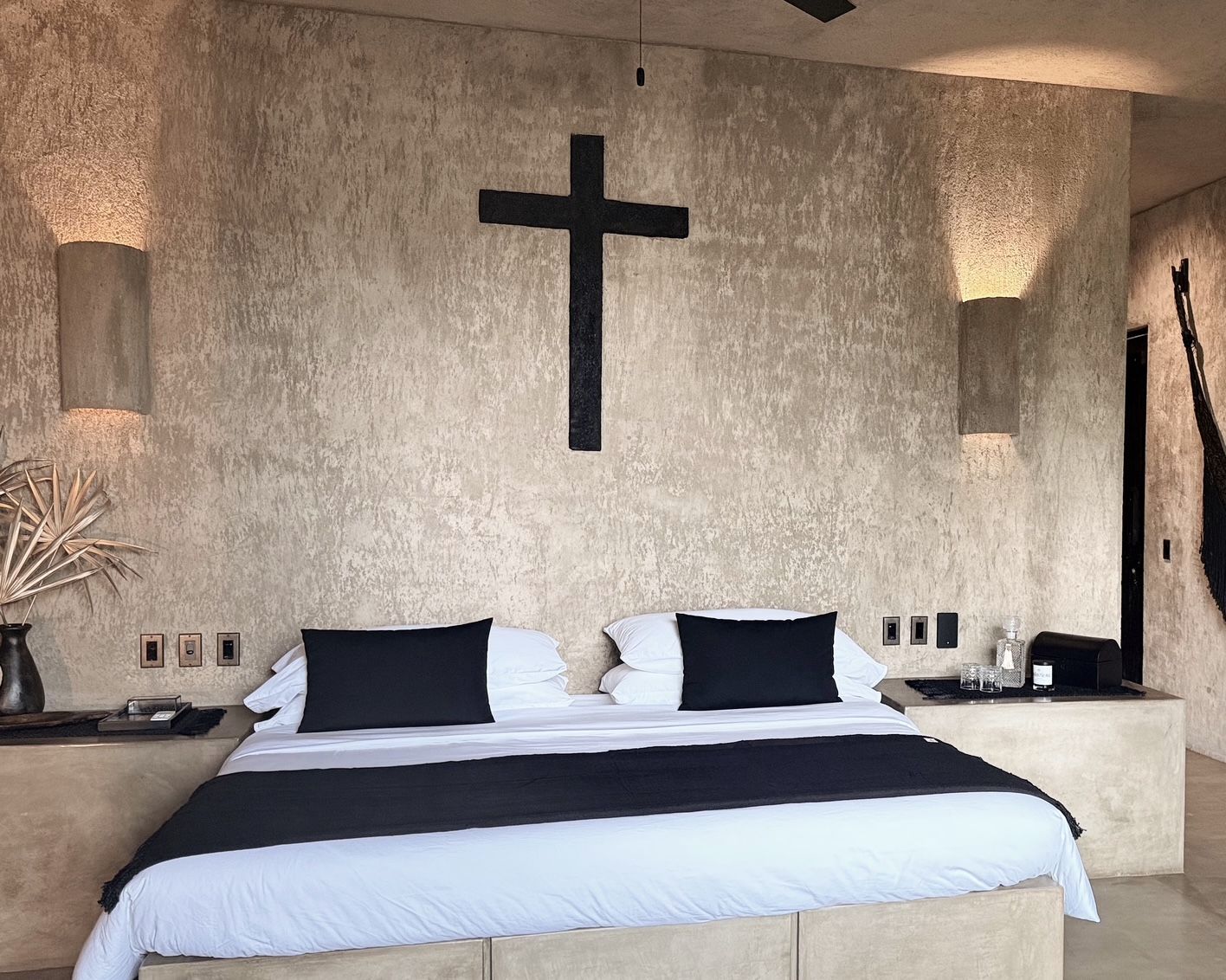 A bedroom with a bed and a cross on the wall.
