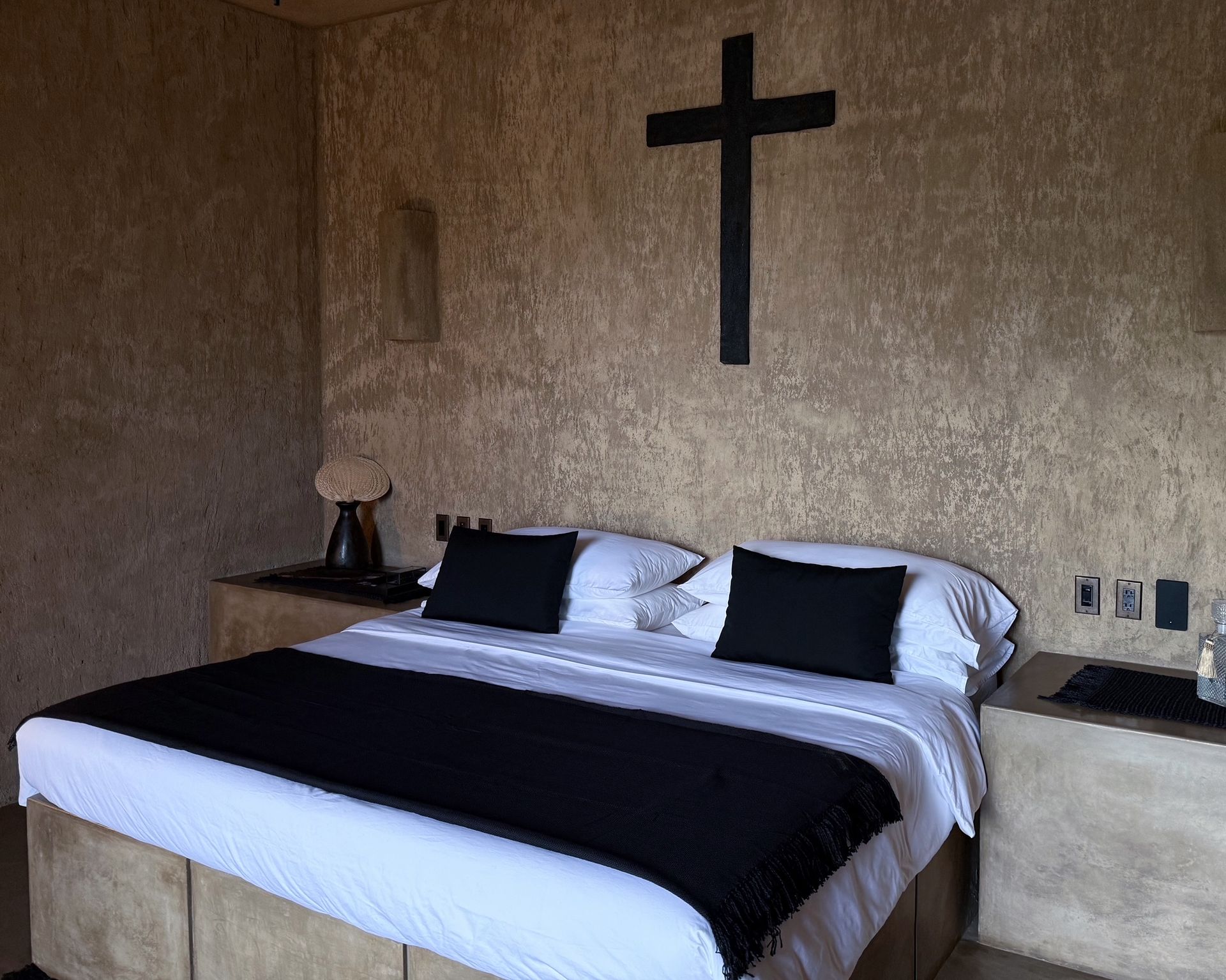 A bedroom with a bed and a cross on the wall
