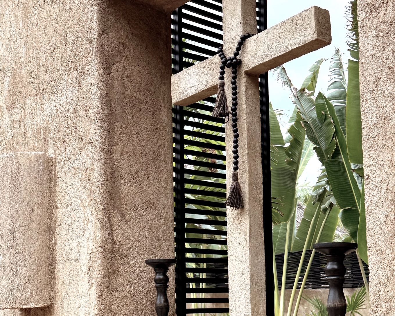 A stone cross with a rosary hanging from it
