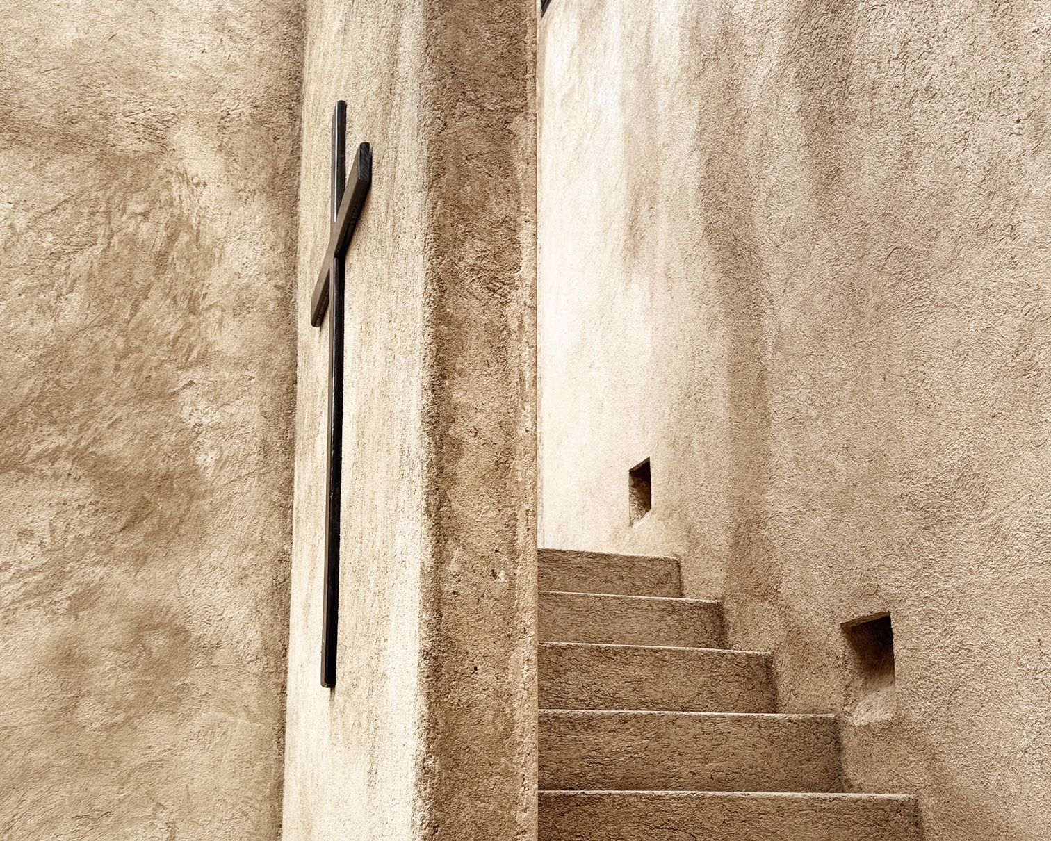 A staircase with a metal railing and a cross on the wall