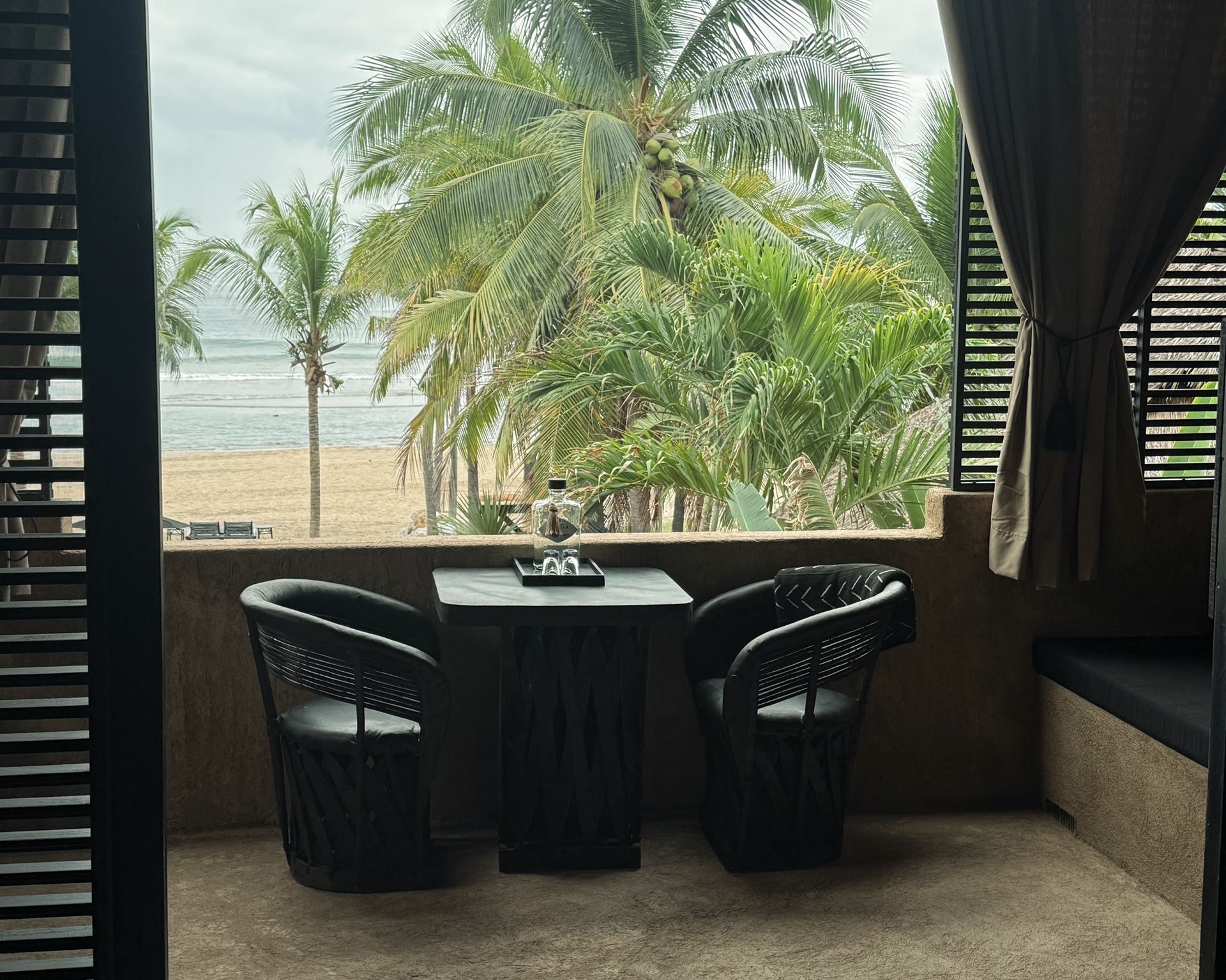 Two chairs and a table on a balcony overlooking the ocean