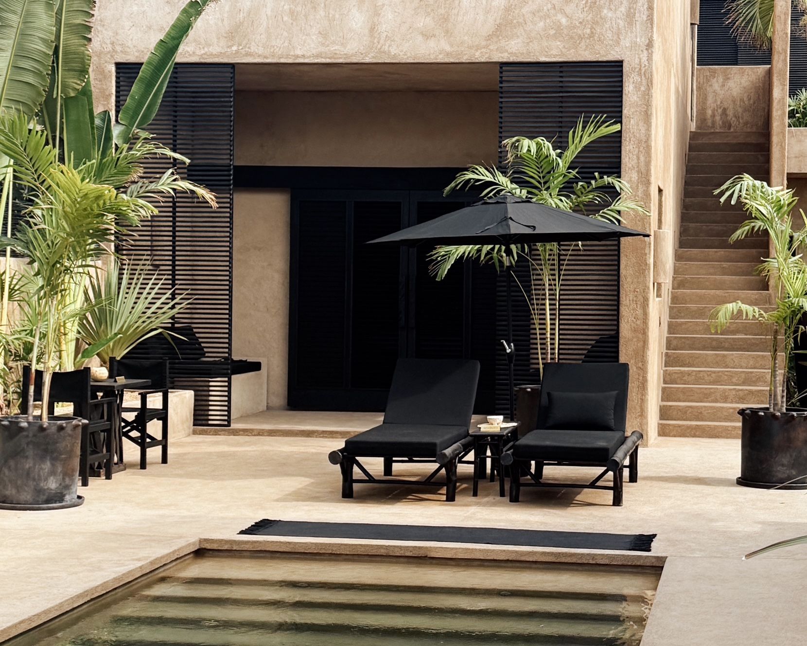 A swimming pool with chairs and umbrellas in front of a building