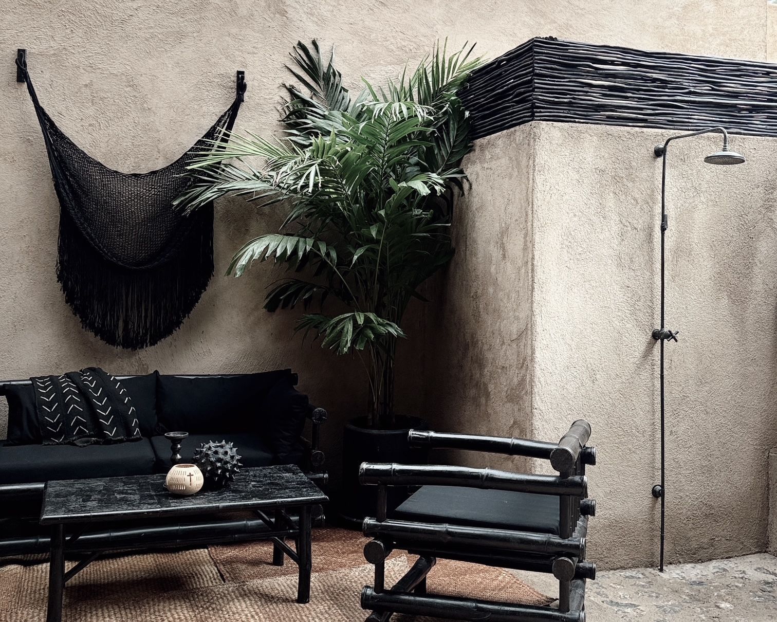 A patio with a couch , chairs , table and a shower.