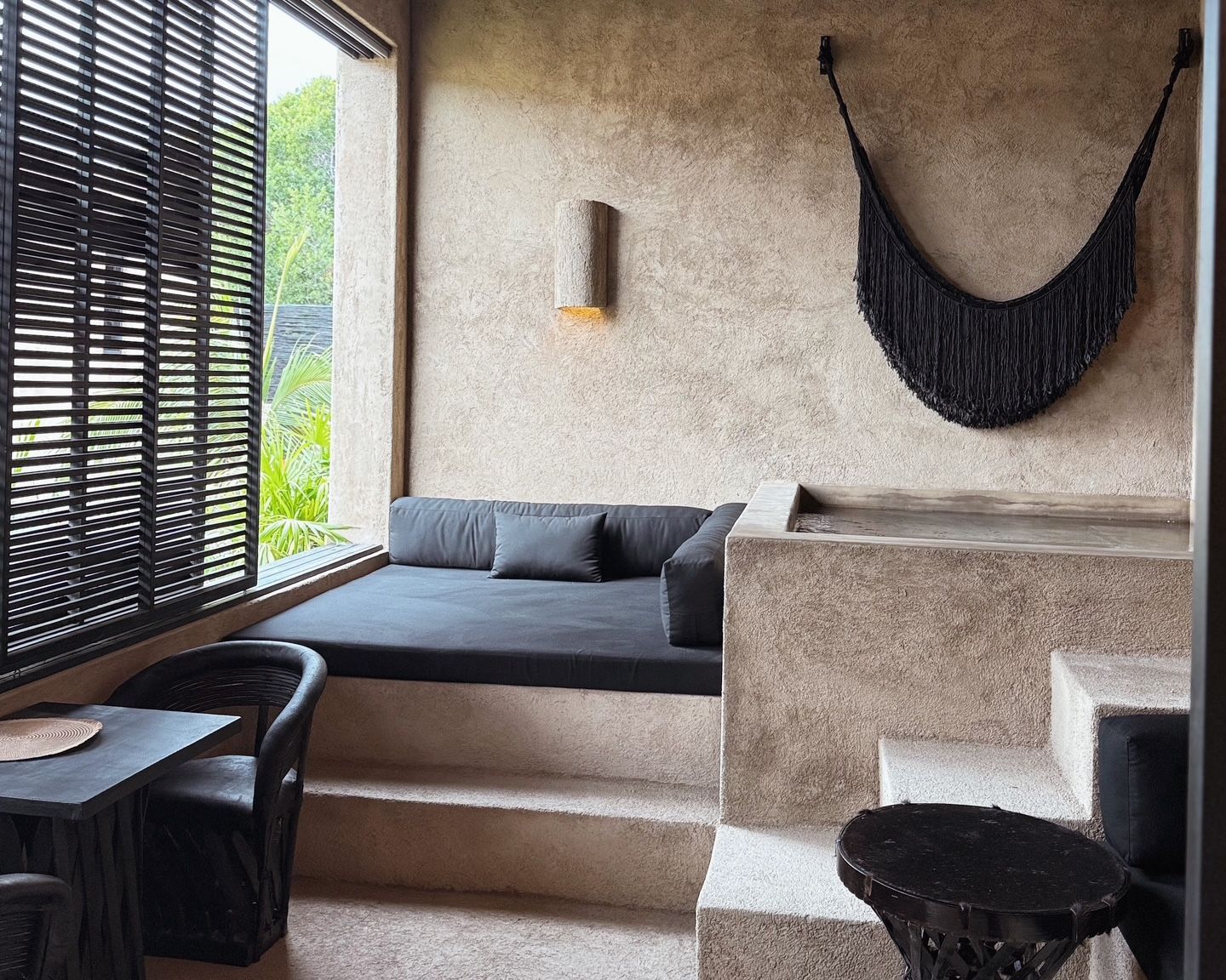 A room with a couch and a hammock on the wall.
