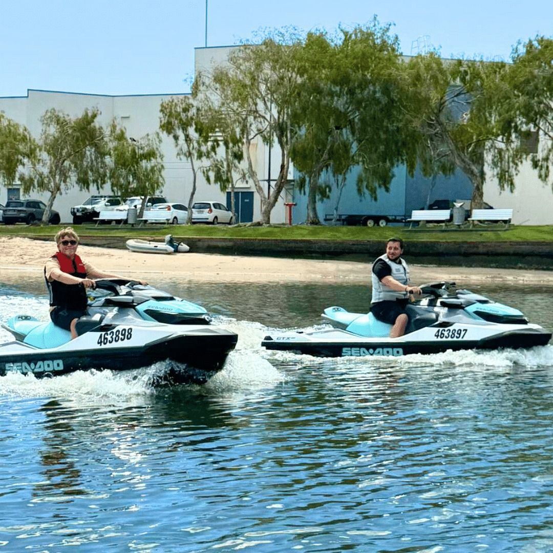 Two people are riding jet skis on a body of water.