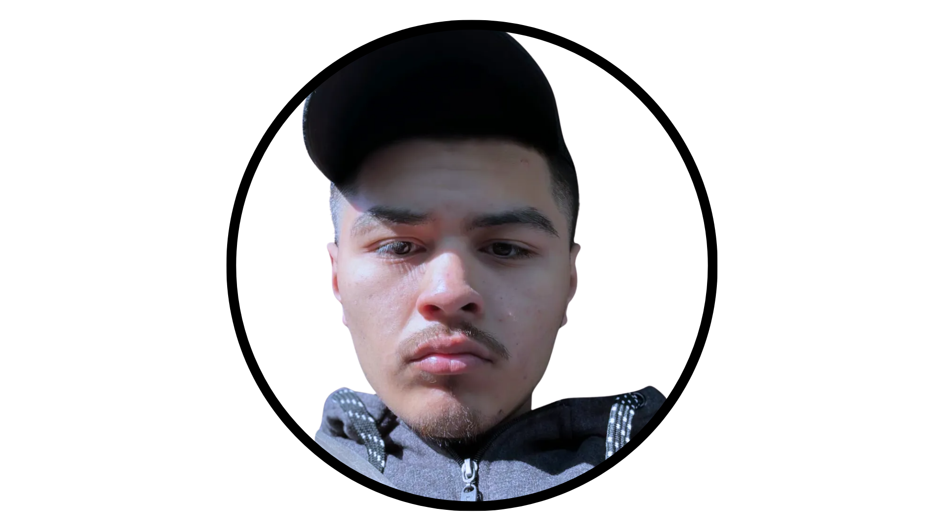 A close-up portrait of a person with short dark hair wearing a black baseball cap and a grey hoodie.