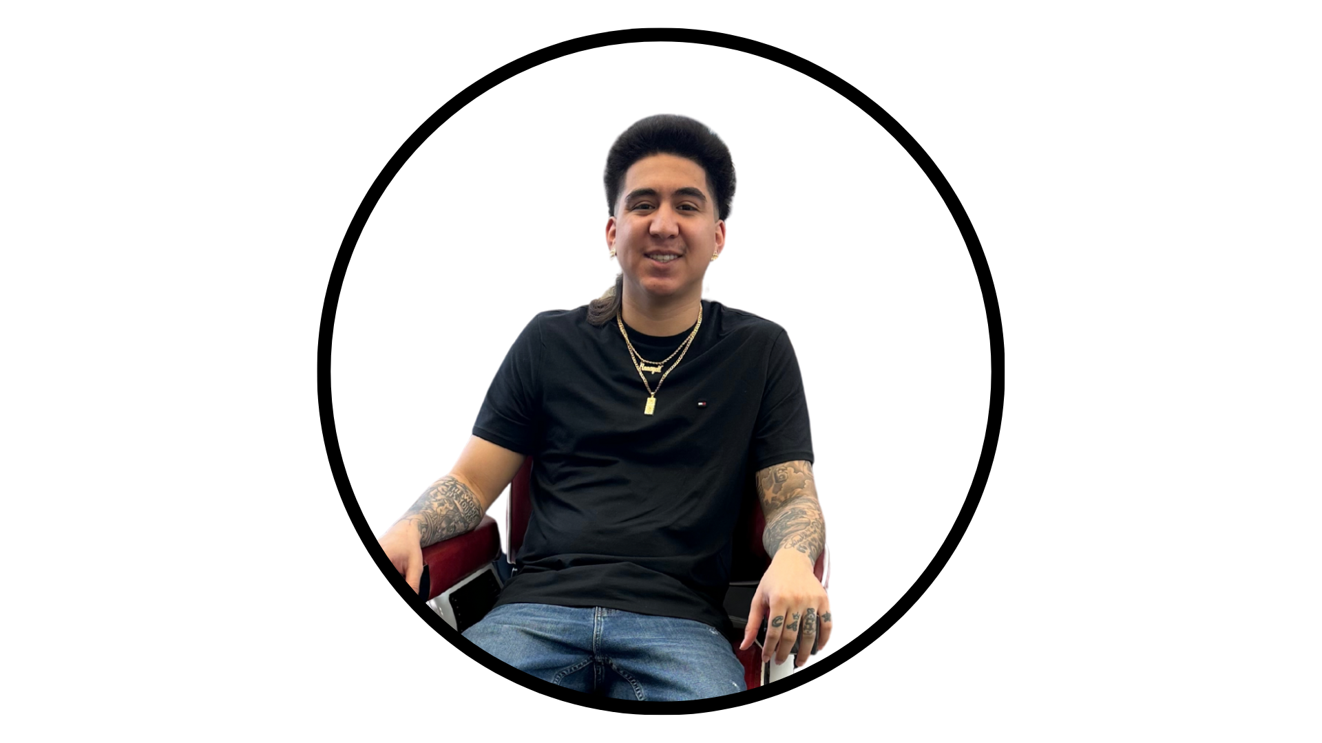 A person with tattoos on their arms sits in a chair against a plain white background, framed by a circular black border.