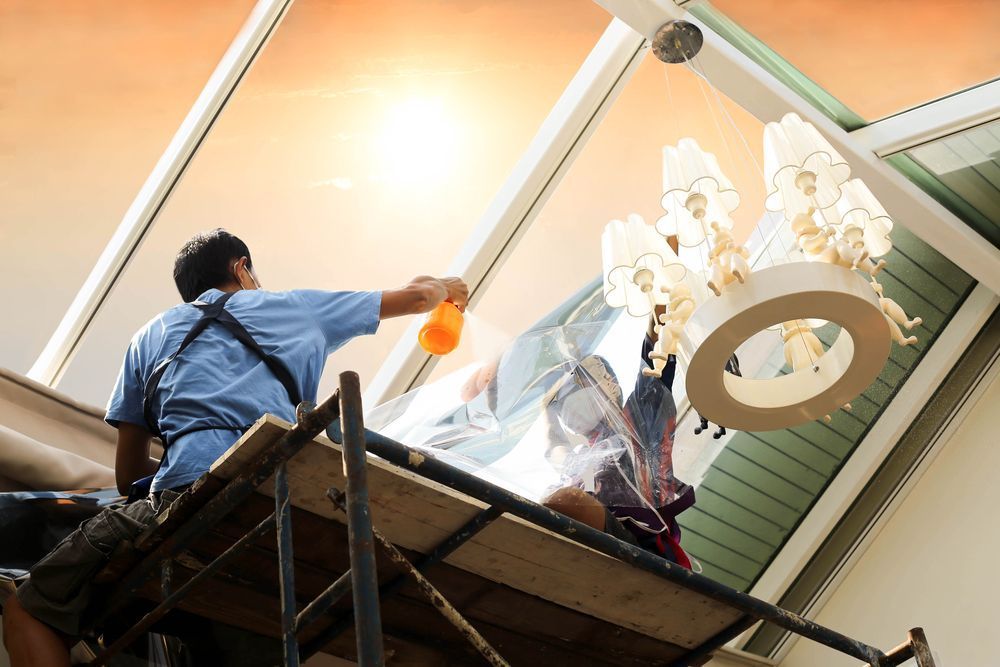 A Man Is Sitting On A Scaffolding Cleaning A Window  — Jay's Tint in Cairns, QLD