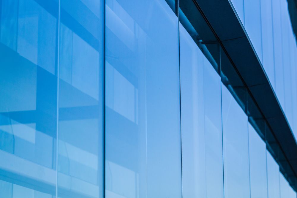 A Close Up Of A Blue Glass Building With A Blue Sky Reflected In The Windows  — Jay's Tint in Smithfield, QLD