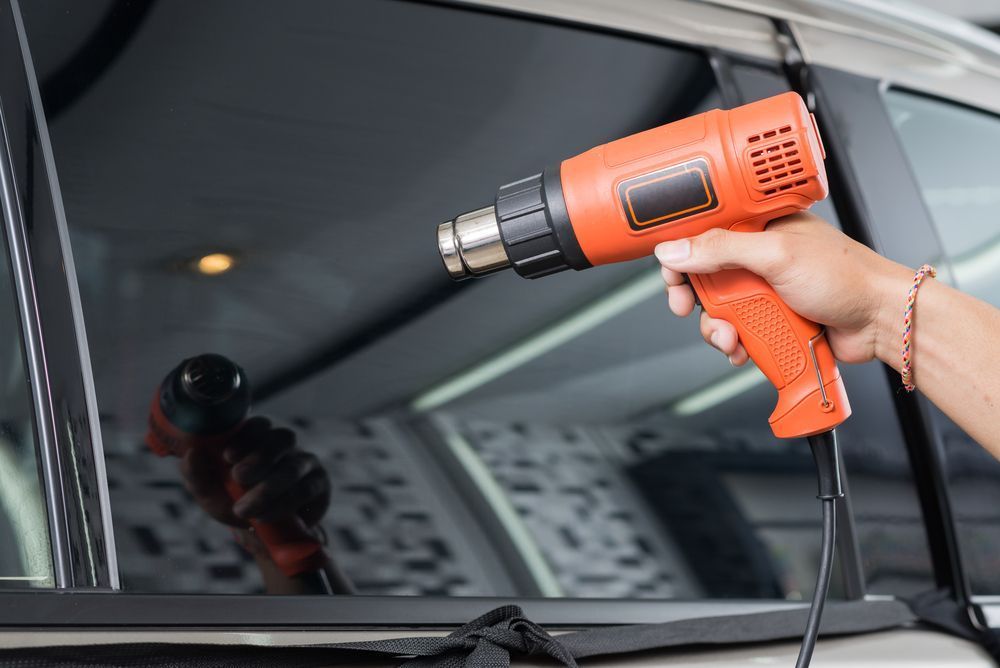 A Person Operates An Electric Heat Gun To Warm A Window — Jay's Tint in Northern Beaches, QLD