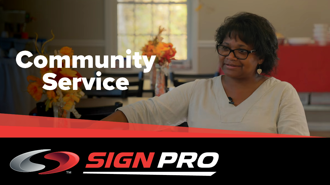 A woman is sitting in front of a sign that says community service.