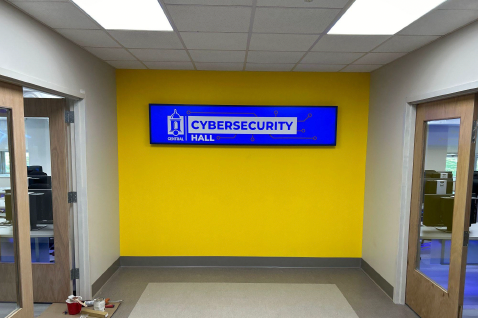 A yellow wall with a blue sign that says cybersecurity