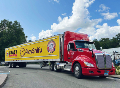A red semi truck with a yellow trailer is parked on the side of the road